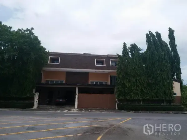 บ้าน ขายในSamut Prakan - มุมมองด้านหน้าบ้านเดี่ยวหลังใหญ่ติดถนน พร้อมประตูรั้วและต้นไม้สูงรายรอบ.