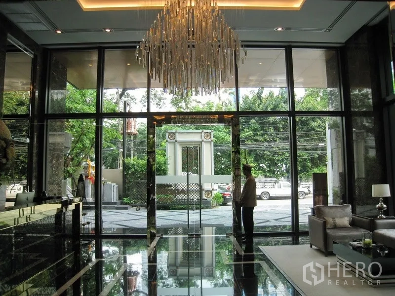 Condominium for rent in Watthana, Bangkok - Grand lobby entrance with chandelier, marble floors and full-height glass framing leafy views.