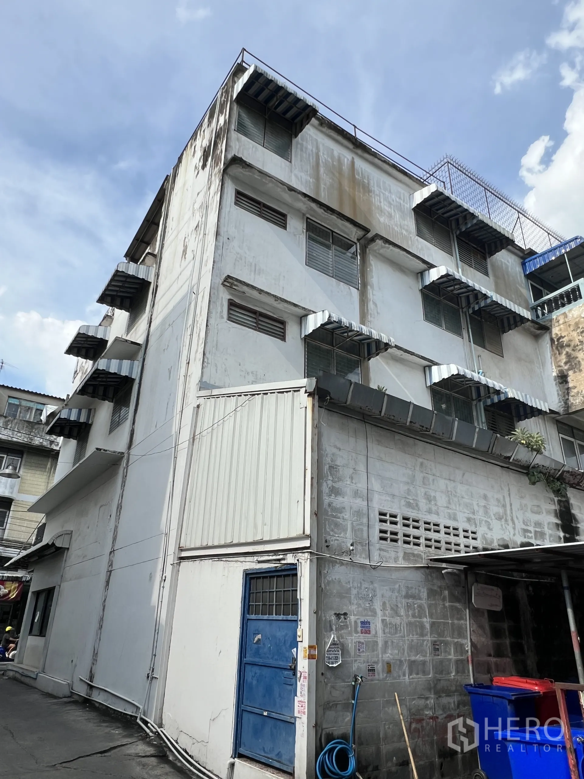 零售空间 出租在Suan Luang, Bangkok - 建筑后侧外观，多层结构，蓝色服务门与外挑雨棚。