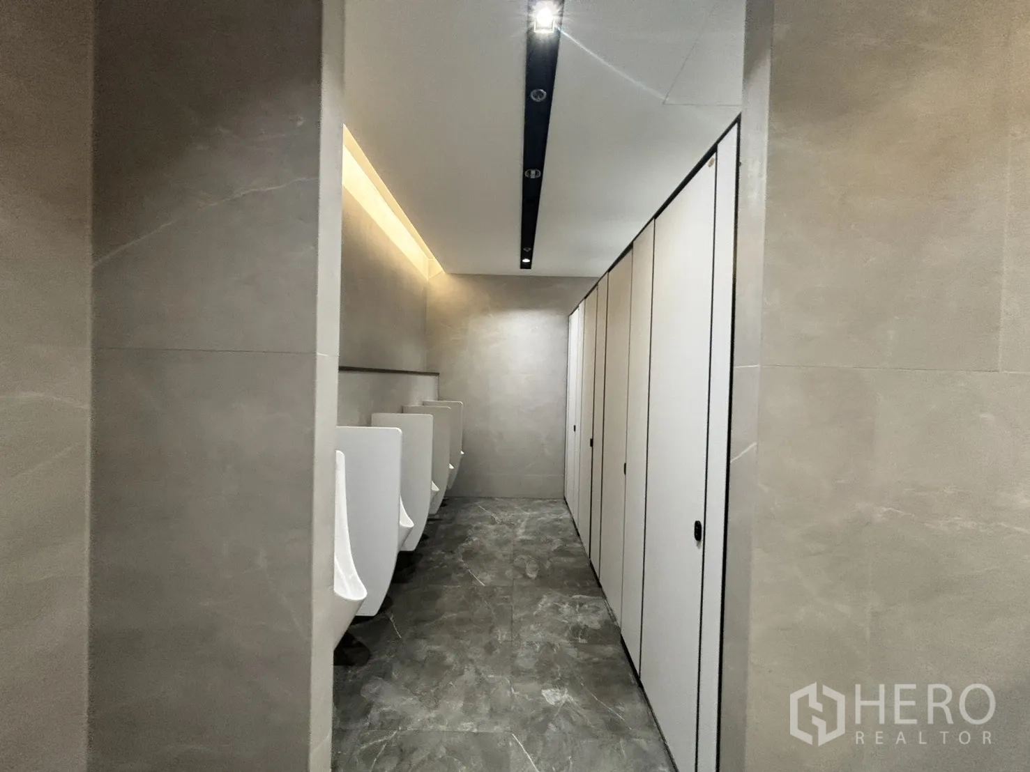 Office Space for rent in Huai Khwang, Bangkok - Restroom with urinals and partitioned toilet stalls finished in grey tiles.