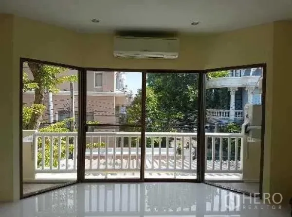 Townhouse for rent in Khlong Toei, Bangkok - Sliding glass doors opening to a balcony with leafy neighborhood views.