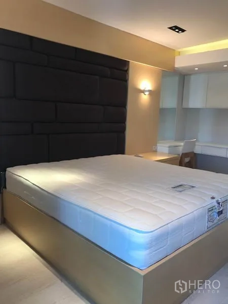 Condominium for rent or sale in Watthana, Bangkok - Bedroom featuring king-size platform bed, dark padded headboard, and built-in cabinetry.