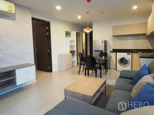 Condominium for rent in Sathon, Bangkok - Open-plan living and dining area with sofa, dining set and kitchen with washer.