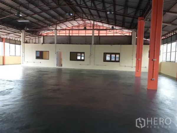 货栈 出租在Khlong Sam Wa, Bangkok - 高挑钢结构屋顶的仓库内部，橙色立柱与环氧地坪，带内置办公室窗。
