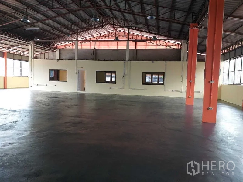 货栈 出租在Khlong Sam Wa, Bangkok - 高挑钢结构屋顶的仓库内部，橙色立柱与环氧地坪，带内置办公室窗。