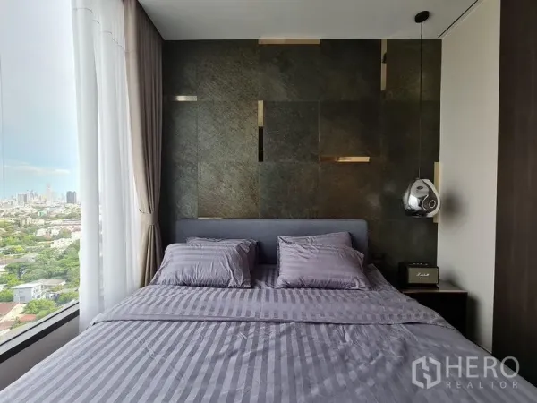 Condominium for rent - Bedroom headboard against textured wall beside full-height window overlooking the city.
