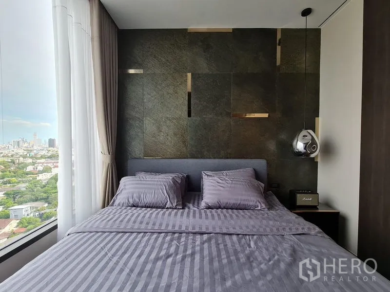 Condominium for rent - Bedroom headboard against textured wall beside full-height window overlooking the city.