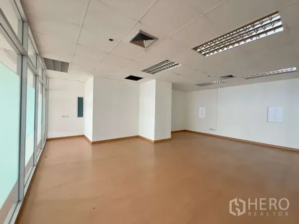 办公空间 出租在Chatuchak, Bangkok - 角落办公区，磨砂玻璃墙、吊顶灯具与复合木地板。