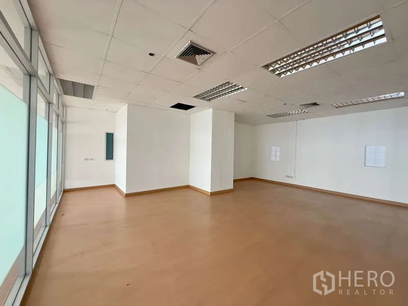 办公空间 出租在Chatuchak, Bangkok - 角落办公区，磨砂玻璃墙、吊顶灯具与复合木地板。