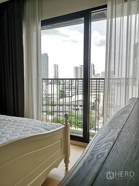 Condominium for rent or sale in Phaya Thai, Bangkok - Bedroom with floor-to-ceiling glass doors opening to a balcony and city view.