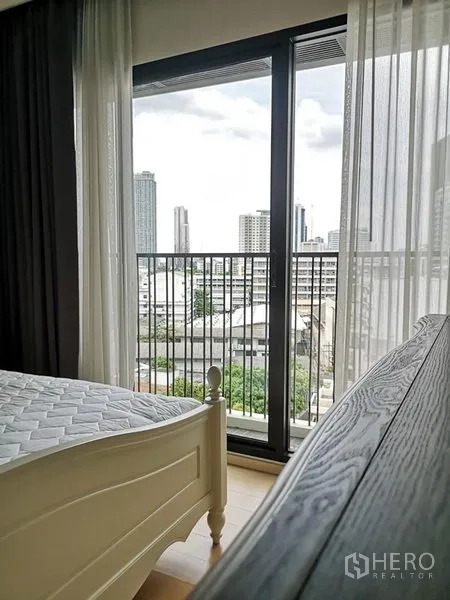 Condominium for rent or sale in Phaya Thai, Bangkok - Bedroom with floor-to-ceiling glass doors opening to a balcony and city view.