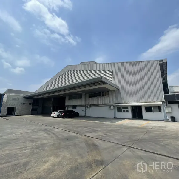 工厂 出租在Bang Phli, Samut Prakan - 金属外墙仓库外观，带大型装卸雨棚、卷闸门与宽阔混凝土作业场地。