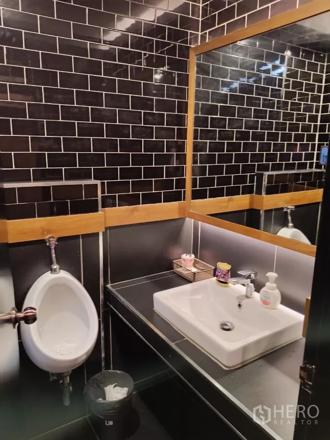 Retail Space for rent - Modern restroom with black subway tiles, sink and urinal.