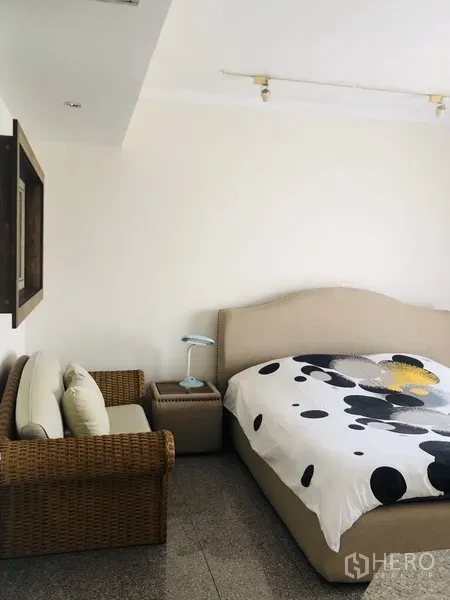 คอนโด ให้เช่าในWatthana, Bangkok - มุมห้องนอนอบอุ่น มีโซฟาหวาย โต๊ะข้างเตียง และชุดเครื่องนอนโทนสบายตา