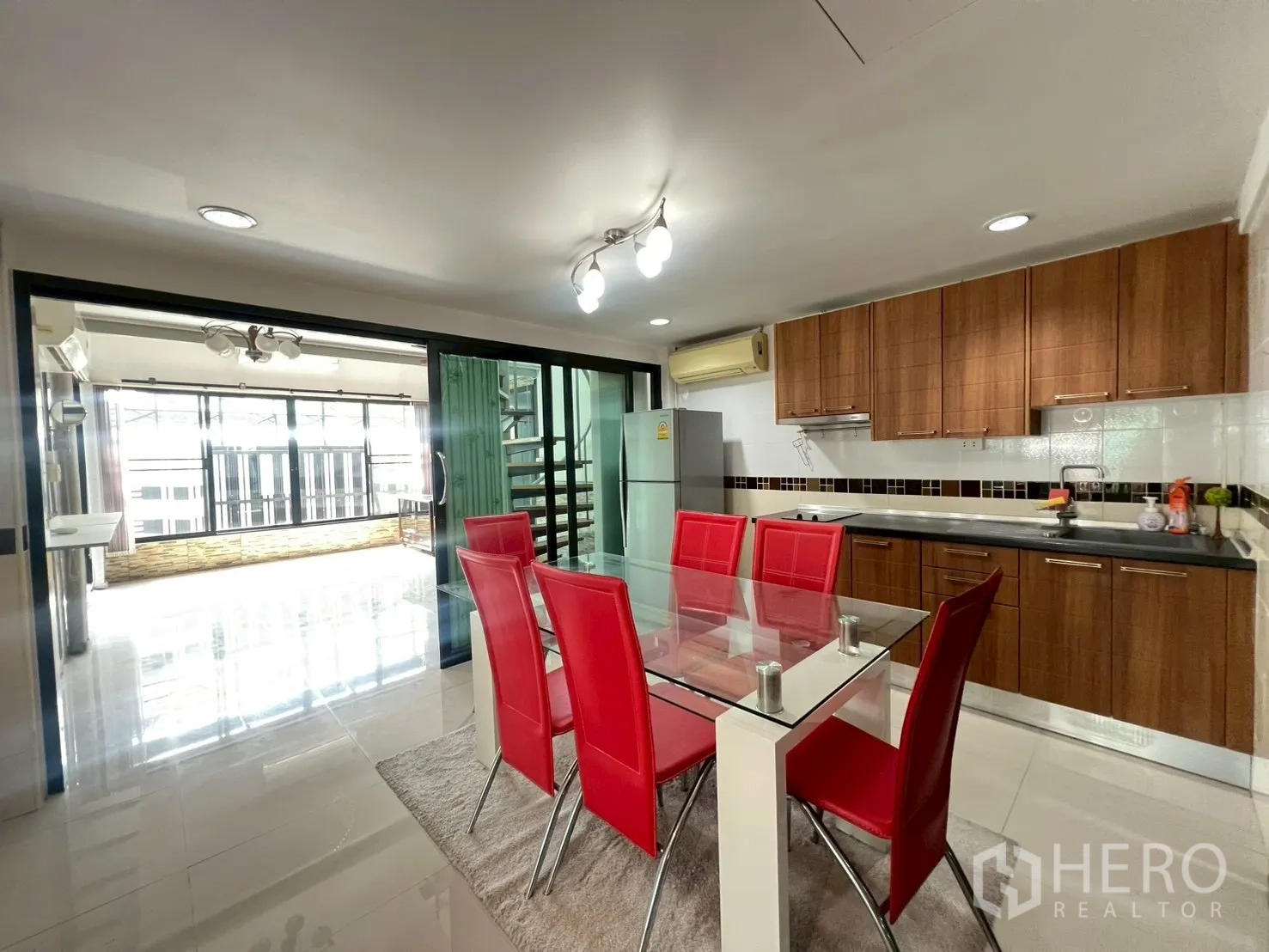 Detached House for rent or sale in Wang Thonglang, Bangkok - Fitted kitchen with wooden cabinets, glass dining table and red chairs.