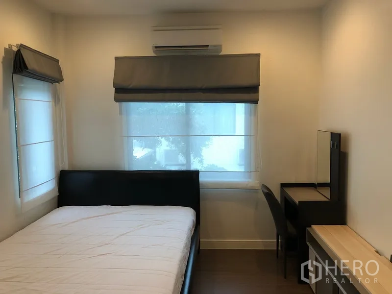 Detached House for rent or sale in Bang Kapi, Bangkok - Cozy guest bedroom with bed, study desk, air conditioner and roman blinds.