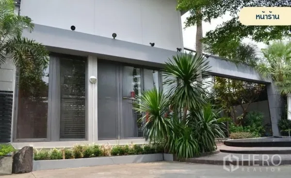 零售空间 出租在Wang Thonglang, Bangkok - 曼谷旺通朗现代店面外立面，落地玻璃与热带绿化相映成趣。