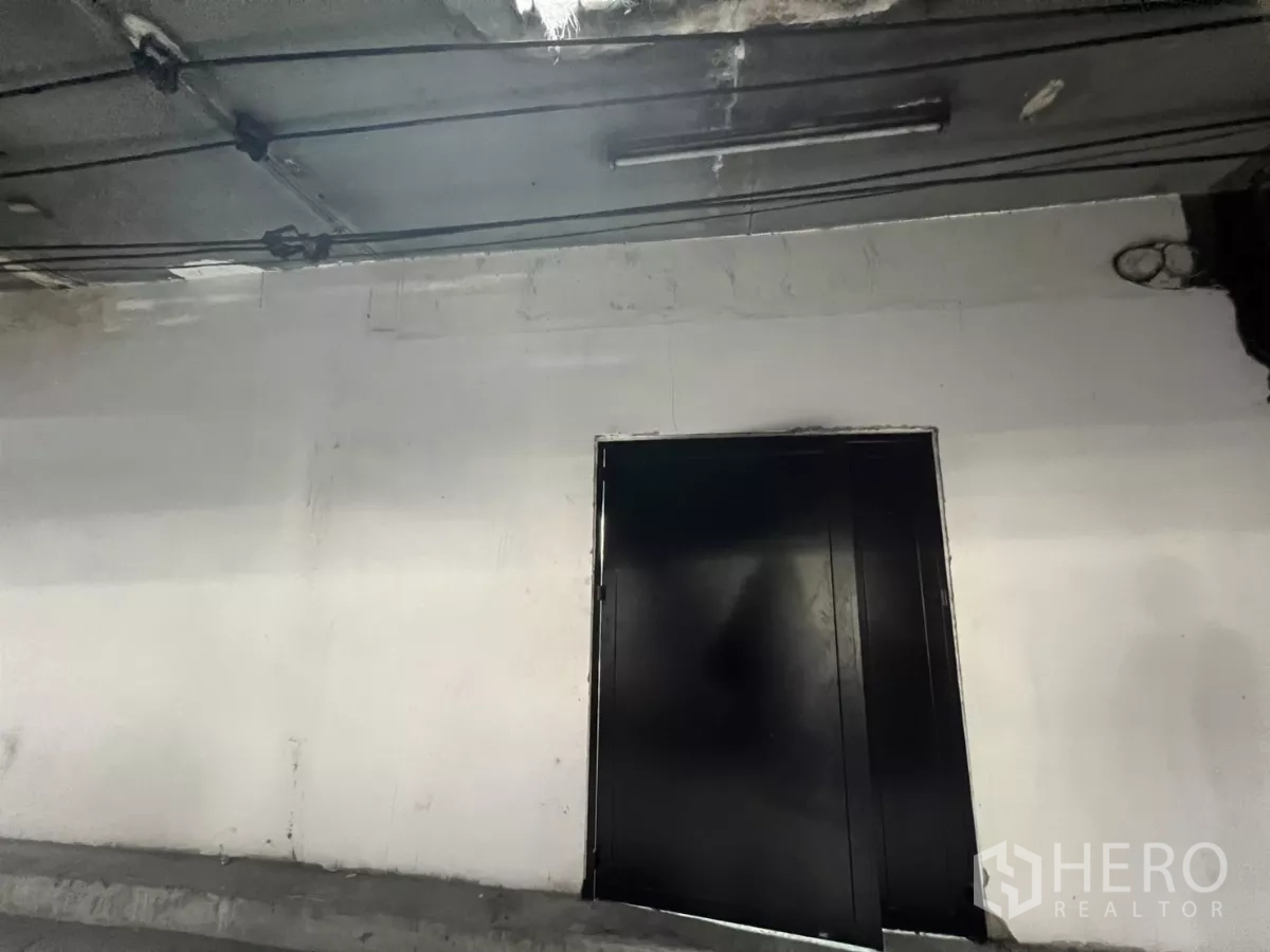 店屋 出售在Suan Luang, Bangkok - 覆盖走道里的白墙黑色金属双开门。