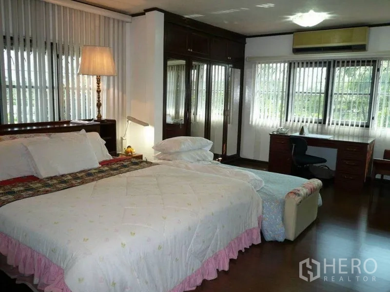 Detached House for rent in Bang Kapi, Bangkok - Spacious bedroom with large bed, mirrored wardrobes and a desk by the windows.