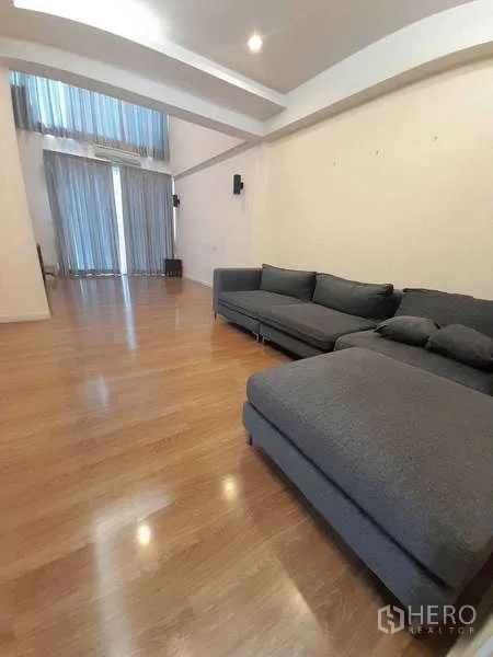 ทาวน์เฮาส์ ให้เช่าในKhlong Toei, Bangkok - ห้องนั่งเล่นกว้างโซฟาเข้ามุมสีเทา เพดานสูง