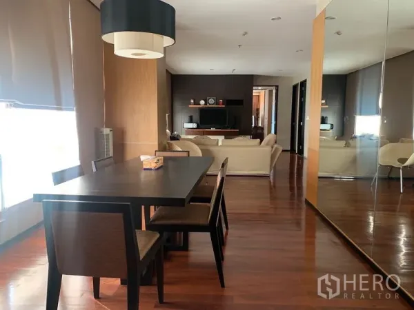 Condominium for rent - Dining table for four beside a mirrored wall, leading to a cozy living zone with TV console.