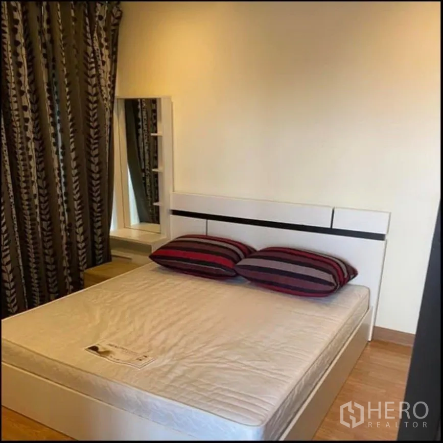 Condominium for rent in Watthana, Bangkok - Bedroom with double bed, striped pillows, blackout curtains, and vanity mirror.