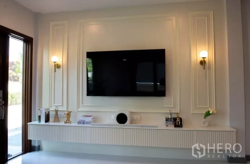 Detached House for rent in Bang Phli, Samut Prakan - Feature wall with mounted TV, twin sconces and a floating console cabinet.