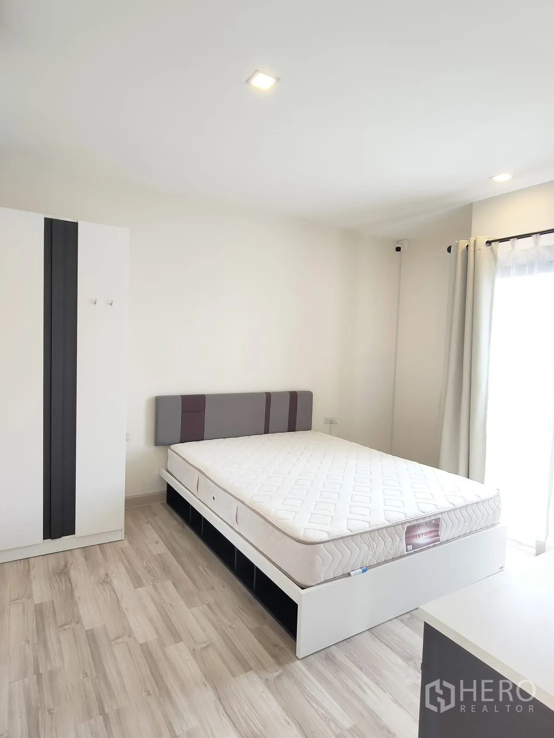 Townhouse for rent in Saphan Sung, Bangkok - Light-filled bedroom with double bed, wardrobe, wood-style flooring and window curtains.