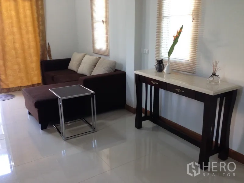 独立式住宅 出售在Phra Khanong, Bangkok - 温馨客厅，棕色转角沙发与玄关桌，临高窗。