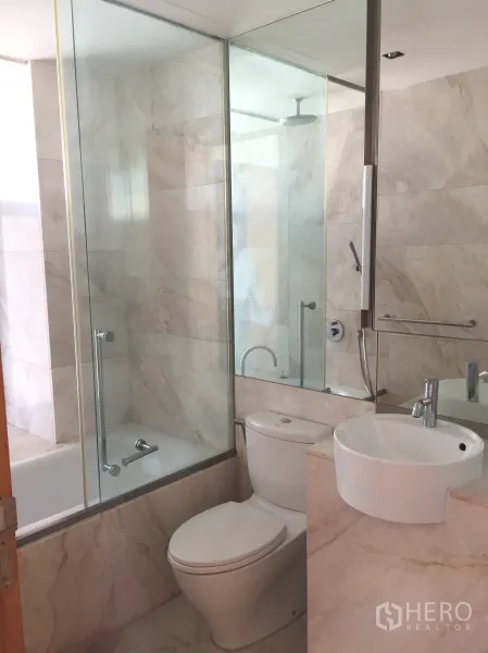 Condominium for sale in Sathon, Bangkok - Marble‑tiled bathroom with glass shower enclosure, bathtub, vanity and toilet.