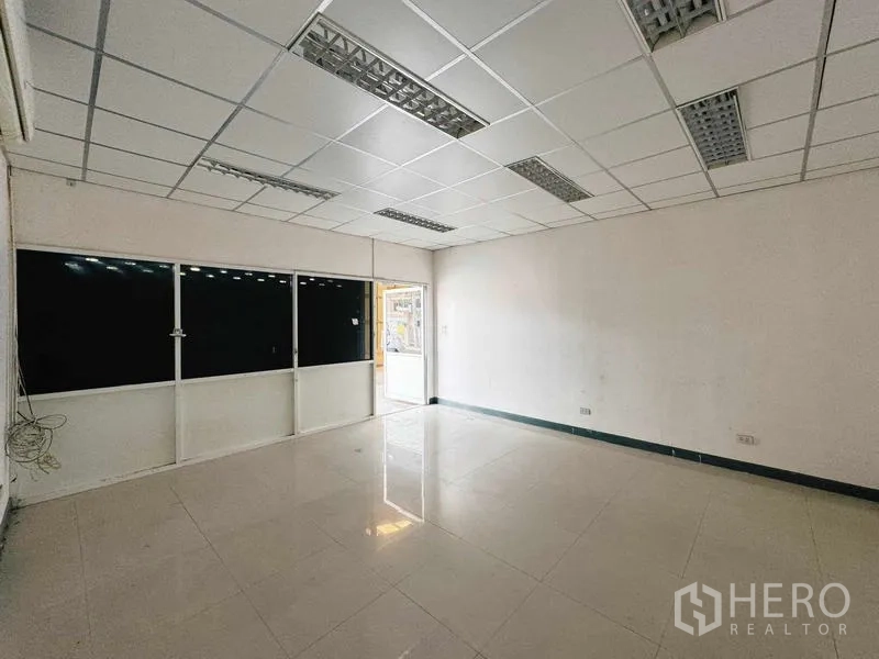 Warehouse for rent in Din Daeng, Bangkok - Facade with office glass entrance beside metal-clad wall and gate.