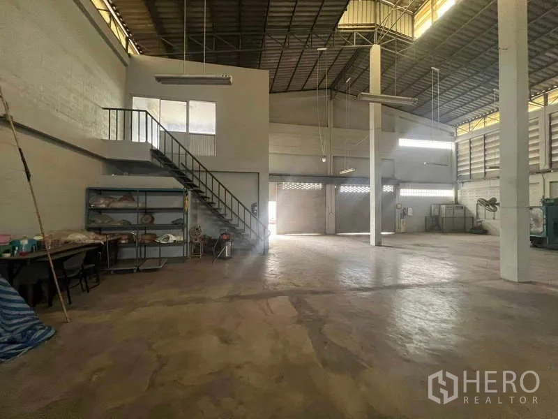 Warehouse for rent in Lam Luk Ka, Pathum Thani - Open production area with a staircase to the mezzanine, shelving, and a concrete floor.