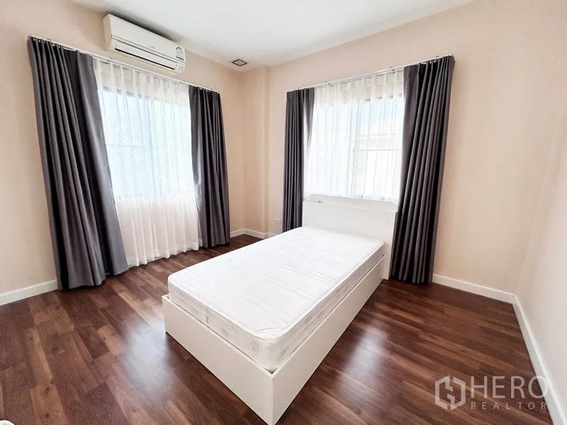Detached House for rent or sale in Prawet, Bangkok - Bright bedroom with double bed, curtains, and wood floors.