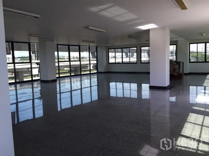 Standalone for rent in Bang Phli, Samut Prakan - Open-plan workspace with central column and panoramic windows overlooking nearby roadway.