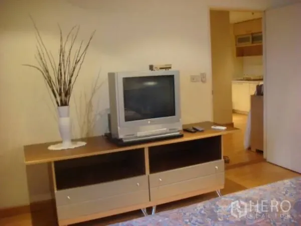 คอนโด ให้เช่าในPathum Wan, Bangkok - ห้องนั่งเล่นพื้นไม้ พร้อมชั้นวางทีวี เชื่อมต่อไปยังห้องนอน