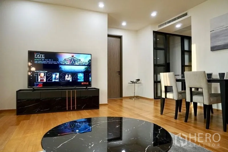 คอนโด ให้เช่าในKhlong Toei, Bangkok - โซนรับแขกและทานอาหาร เปิดโล่ง มีคอนโซลทีวี ไฟดาวน์ไลท์ และพื้นไม้