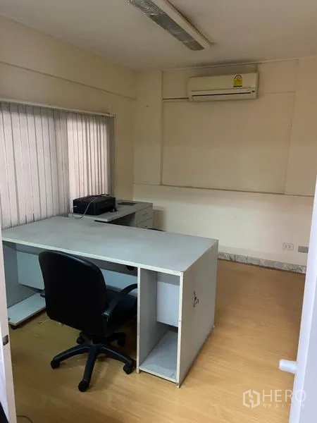 Townhouse for rent in Khlong Toei, Bangkok - Small study room with desk, chair, air-conditioning unit, and vertical blinds.