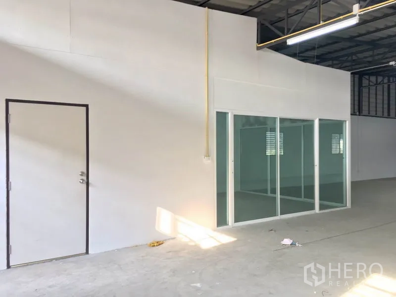 คลังสินค้า ให้เช่าในLam Luk Ka, Pathum Thani - มุมใกล้ของห้องออฟฟิศกั้นกระจกแบบบานเลื่อน พร้อมประตูบริการด้านข้างภายในโกดัง.