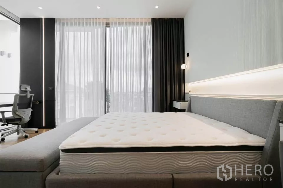 ทาวน์เฮาส์ ขายในChatuchak, Bangkok - ห้องนอนมาสเตอร์ ประตูกระจกสู่ระเบียง โต๊ะทำงาน และเตียงบุผ้า