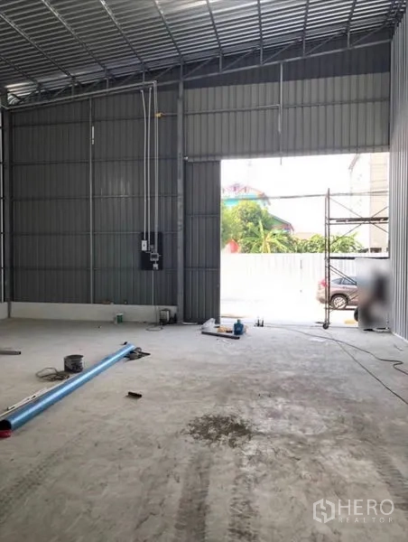 货栈 出租在Bueng Kum, Bangkok - 仓库内部，高钢结构屋顶，大型推拉门，混凝土地面与电力面板。
