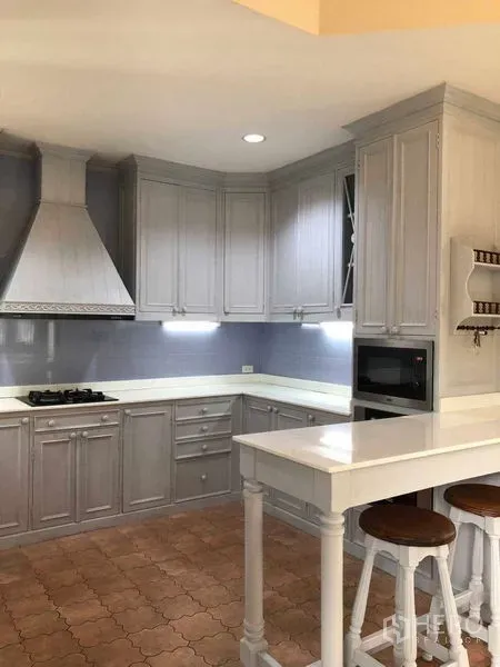 独立式住宅 出租在Bang Na, Bangkok - U形厨房，灰色柜体、烟机、吧台与赤陶地砖。