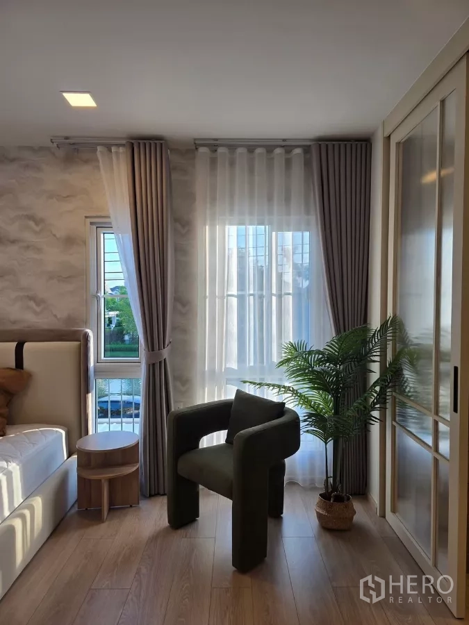 Detached House for rent in Bang Phli, Samut Prakan - Master bedroom corner with armchair, side tables and greenery by the windows.