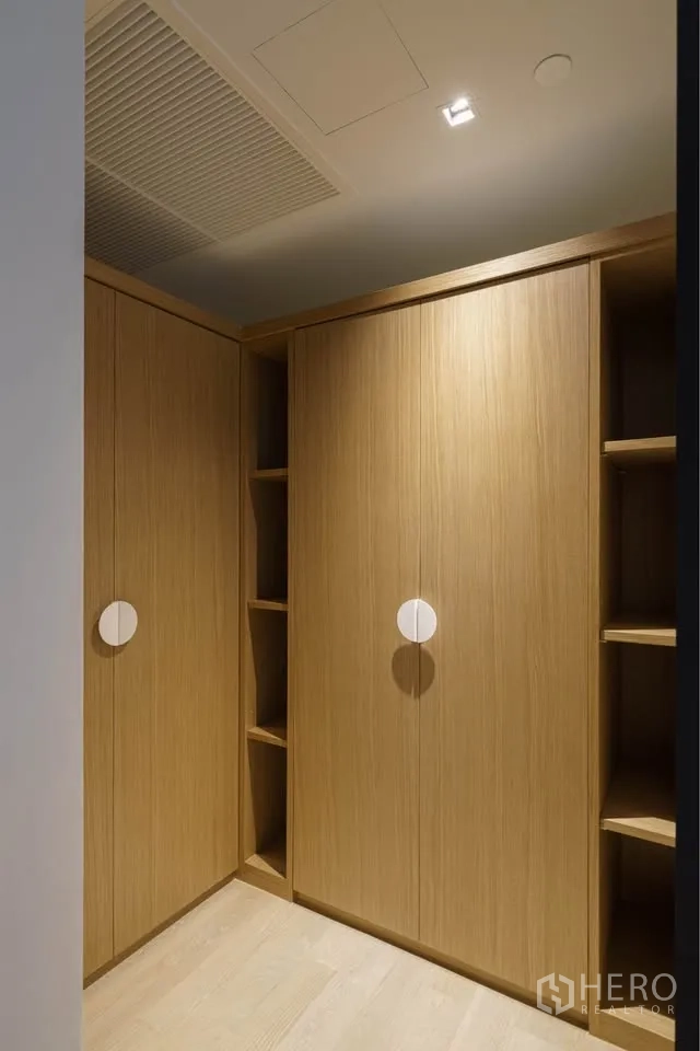 Condominium for rent in Bang Rak, Bangkok - Walk-in closet with built-in wood wardrobes and open shelving.