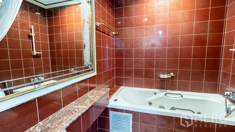 Townhouse for rent in Khlong Toei, Bangkok - Red‑tiled bathroom with bathtub and marble ledge.