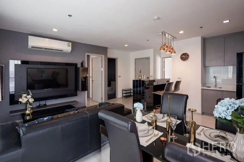 คอนโด ให้เช่าในKhlong Toei, Bangkok - โซนนั่งเล่น–ทานอาหาร มีโซฟาหนัง โต๊ะทานข้าว และครัวบิวท์อินสีเทา