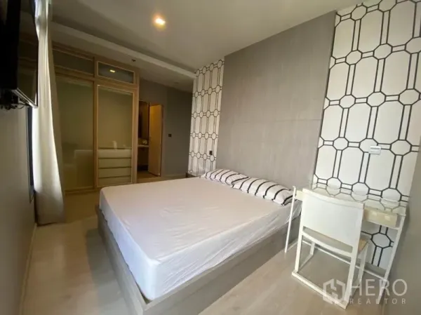 คอนโด ให้เช่าในWatthana, Bangkok - ห้องนอนหลักพร้อมผนังตกแต่ง เตียง โต๊ะทำงาน และตู้เสื้อผ้าบานเลื่อนกระจก