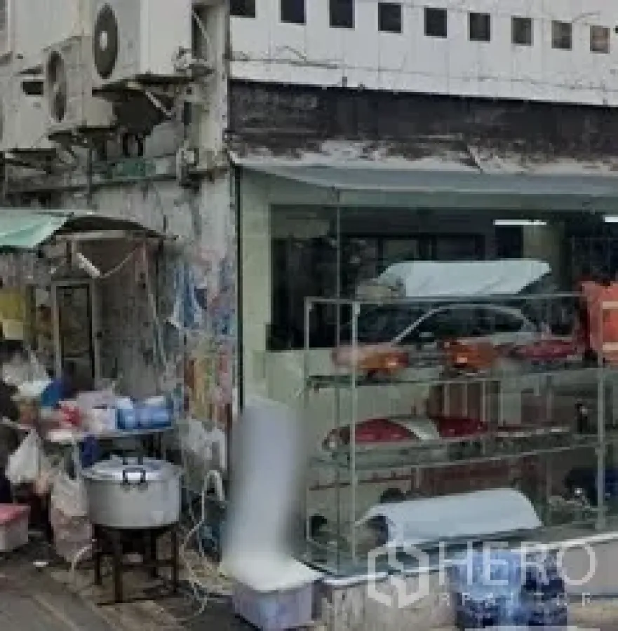 Shophouse for rent in Sathon, Bangkok - Street-corner shophouse with large glass storefront, display shelving and cooking setup in Sathon, Bangkok.