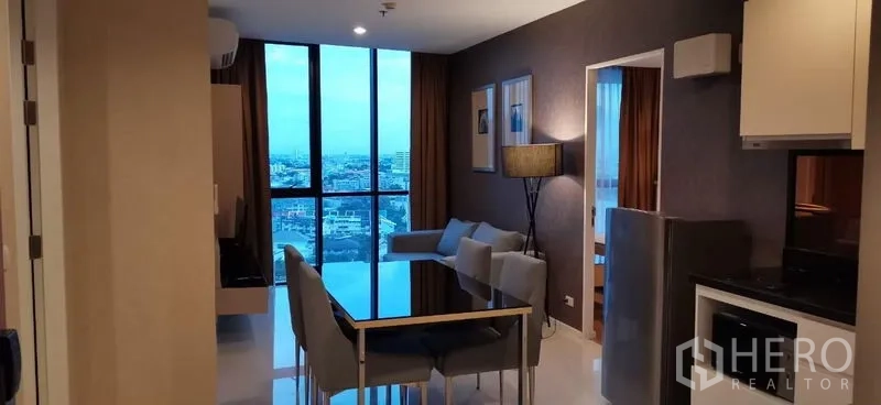 公寓 出租在Watthana, Bangkok - 傍晚的客餐厅，面对整面高窗与城市夜景。