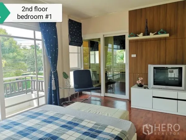 บ้าน ให้เช่า - ห้องนอนชั้นสองสว่าง พื้นไม้ หน้าต่างบานใหญ่ ผ้าม่านสีน้ำเงิน พร้อมตู้ทีวีและทางออกสู่ระเบียง