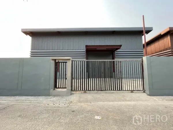 Warehouse for rent in Khlong Sam Wa, Bangkok - Front view of a secure steel-clad warehouse with sliding gate and high perimeter wall in Bangkok.